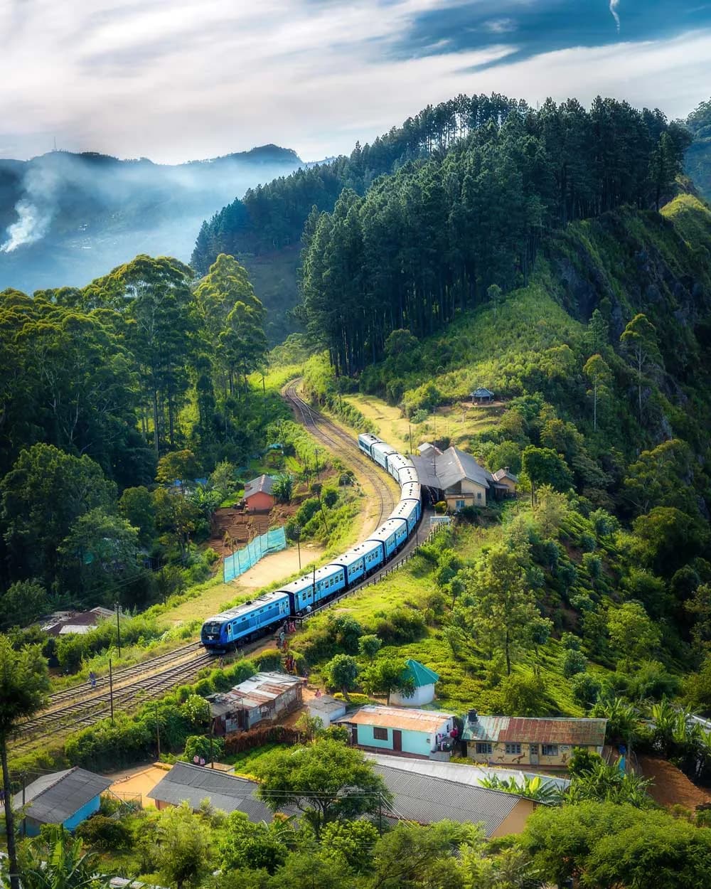 Blue train crossing a stone arch bridge through Sri Lankan tea country